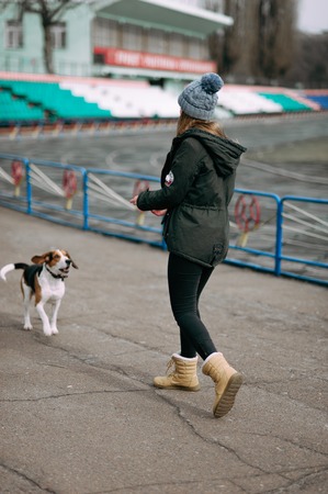 Young hipster girl with her pet estonian hound dog playing and having fun outdoor in the park.の写真素材