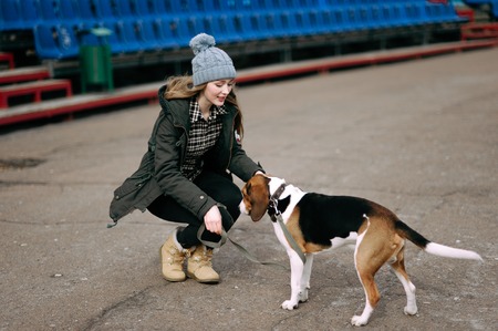 Young hipster girl with her pet estonian hound dog playing and having fun outdoor in the park.の写真素材