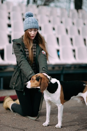 Young hipster girl with her pet estonian hound dog playing and having fun outdoor in the park.の写真素材