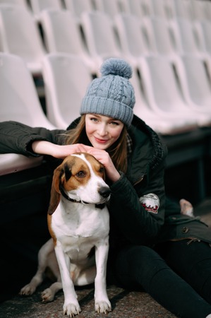 Young hipster girl with her pet estonian hound dog playing and having fun outdoor in the park.