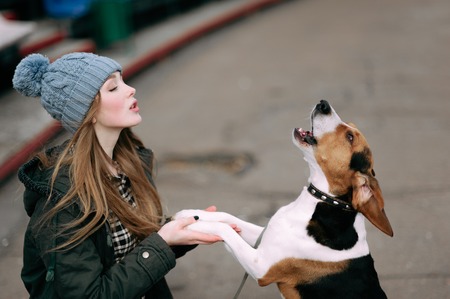 Young hipster girl with her pet estonian hound dog playing and having fun outdoor in the park.