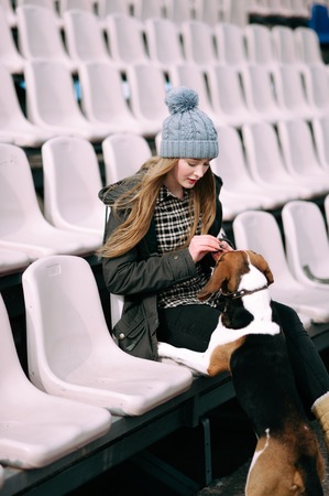 Young hipster girl with her pet estonian hound dog playing and having fun outdoor in the park.の写真素材