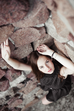 beautiful sad young woman on a stone wall background posing in a black dress, very sensual and emotionalの写真素材