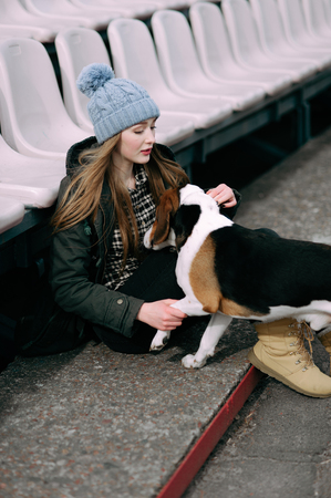 Young hipster girl with her pet estonian hound dog playing and having fun outdoor in the park.の写真素材