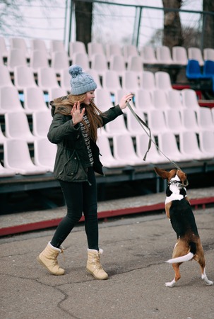 Young hipster girl with her pet estonian hound dog playing and having fun outdoor in the park.の写真素材