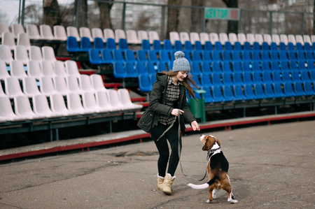 Young hipster girl with her pet estonian hound dog playing and having fun outdoor in the park.の写真素材