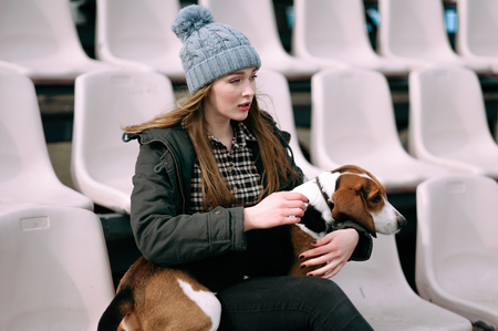 Young hipster girl with her pet estonian hound dog playing and having fun outdoor in the park.の写真素材