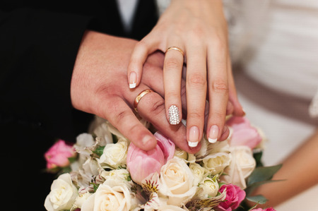 Hands of newlyweds with rings on unusual wedding bouquet.の写真素材