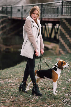 Young hipster girl with her pet estonian hound dog playing and having fun outdoor in the park.の写真素材