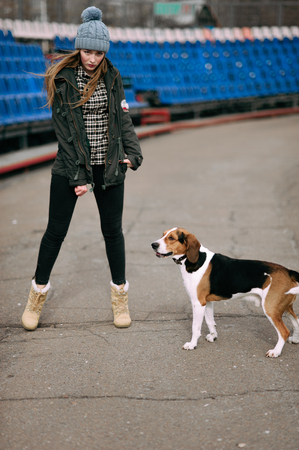 Young hipster girl with her pet estonian hound dog playing and having fun outdoor in the park.の写真素材