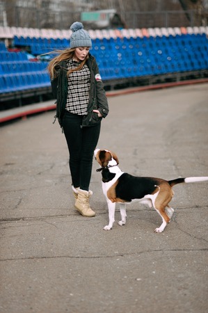 Young hipster girl with her pet estonian hound dog playing and having fun outdoor in the park.の写真素材