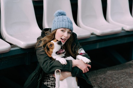 Young hipster girl with her pet estonian hound dog playing and having fun outdoor in the park.の写真素材