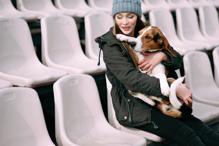 Young hipster girl with her pet estonian hound dog playing and having fun outdoor in the park.
