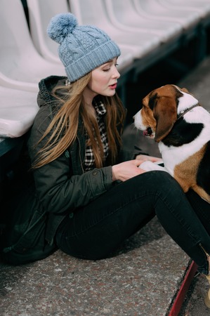 Young hipster girl with her pet estonian hound dog playing and having fun outdoor in the park.の写真素材