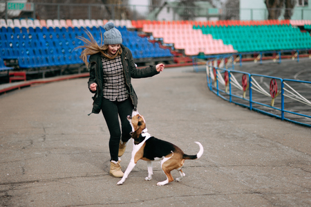 Young hipster girl with her pet estonian hound dog playing and having fun outdoor in the park.の写真素材