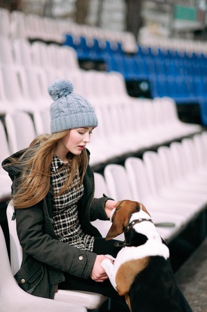 Young hipster girl with her pet estonian hound dog playing and having fun outdoor in the park.の写真素材
