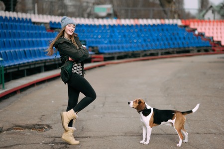 Young hipster girl with her pet estonian hound dog playing and having fun outdoor in the park.の写真素材