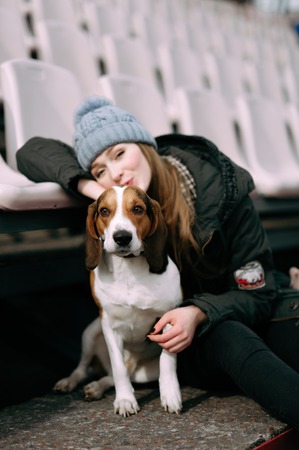 Young hipster girl with her pet estonian hound dog playing and having fun outdoor in the park.の写真素材