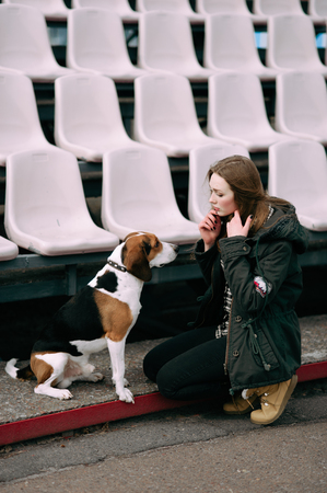 Young hipster girl with her pet estonian hound dog playing and having fun outdoor in the park.の写真素材