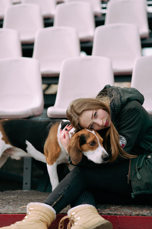 Young hipster girl with her pet estonian hound dog playing and having fun outdoor in the park.の写真素材