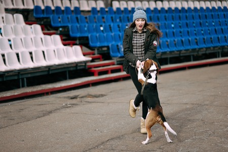 Young hipster girl with her pet estonian hound dog playing and having fun outdoor in the park.の写真素材