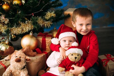 Portrait of happy children with Christmas gift boxes and decorations. Two kids having fun at homeの写真素材
