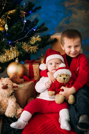 Portrait of happy children with Christmas gift boxes and decorations. Two kids having fun at homeの写真素材