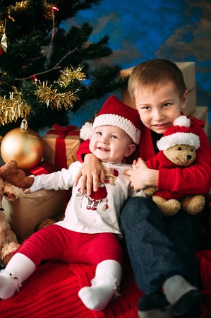 Portrait of happy children with Christmas gift boxes and decorations. Two kids having fun at homeの写真素材