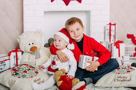 Portrait of happy children with Christmas gift boxes and decorations. Two kids having fun at homeの写真素材
