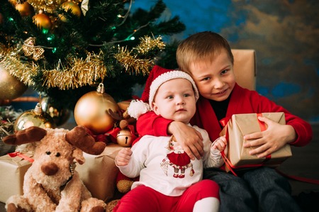 Portrait of happy children with Christmas gift boxes and decorations. Two kids having fun at homeの写真素材