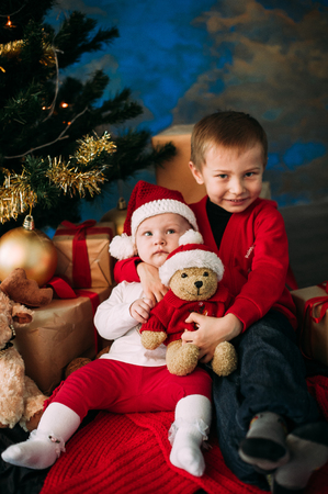 Portrait of happy children with Christmas gift boxes and decorations. Two kids having fun at homeの写真素材