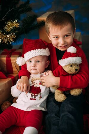 Portrait of happy children with Christmas gift boxes and decorations. Two kids having fun at homeの写真素材