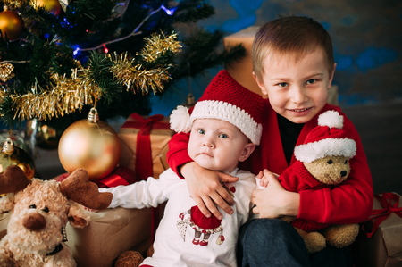 Portrait of happy children with Christmas gift boxes and decorations. Two kids having fun at homeの写真素材