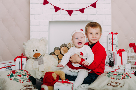 Portrait of happy children with Christmas gift boxes and decorations. Two kids having fun at homeの写真素材