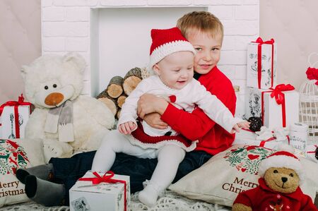 Portrait of happy children with Christmas gift boxes and decorations. Two kids having fun at homeの写真素材