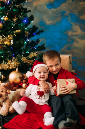 Portrait of happy children with Christmas gift boxes and decorations. Two kids having fun at homeの写真素材