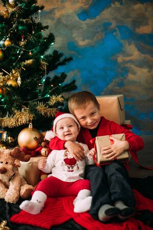 Portrait of happy children with Christmas gift boxes and decorations. Two kids having fun at homeの写真素材