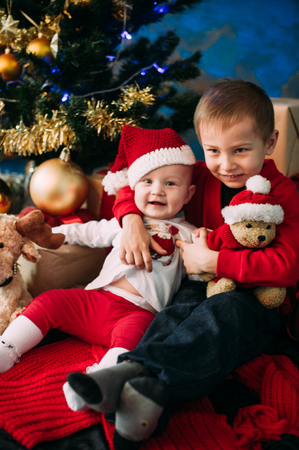 Portrait of happy children with Christmas gift boxes and decorations. Two kids having fun at homeの写真素材