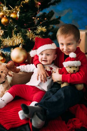 Portrait of happy children with Christmas gift boxes and decorations. Two kids having fun at homeの写真素材
