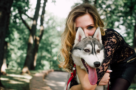 Girl in the park with a dog Husky. The girl with the siberian husky. Delightful girl plays with a Siberian Husky. Girl walking with a hunting dog - the West Siberian husky. Close-up. Fashion photoの写真素材