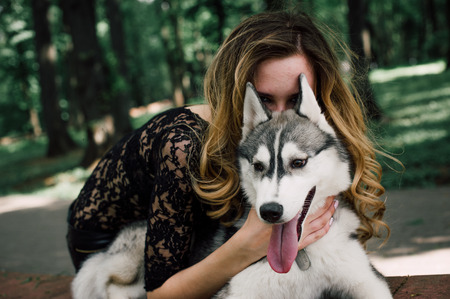 Girl in the park with a dog Husky. The girl with the siberian husky. Delightful girl plays with a...