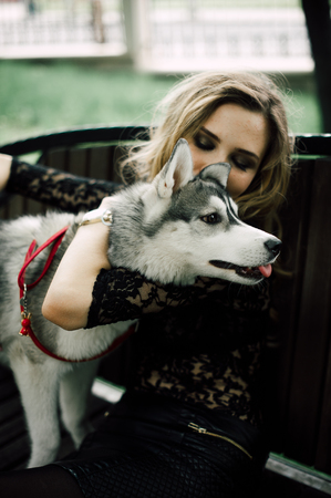 Girl in the park with a dog Husky. The girl with the siberian husky. Delightful girl plays with a Siberian Husky. Girl walking with a hunting dog - the West Siberian husky. Close-up. Fashion photoの写真素材