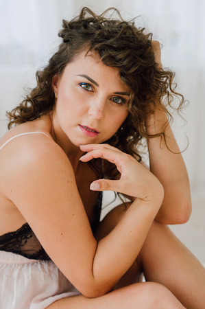 Sexy woman in bed in the morning showing her beautiful body. She doesn't wants to wake up. Awaken with natural light in her bedroom and covered with the bed sheets.の写真素材