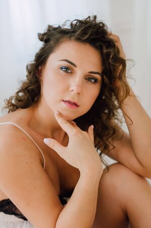 Sexy woman in bed in the morning showing her beautiful body. She doesn't wants to wake up. Awaken with natural light in her bedroom and covered with the bed sheets.の写真素材