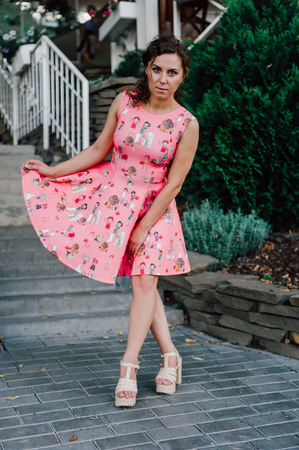 Beautiful brunette girl posing in pink dress outside near tropical plantsの写真素材