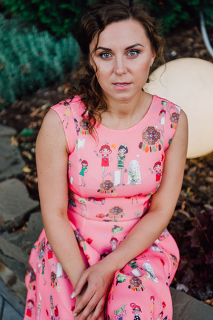 Beautiful brunette girl posing in pink dress outside near tropical plantsの写真素材