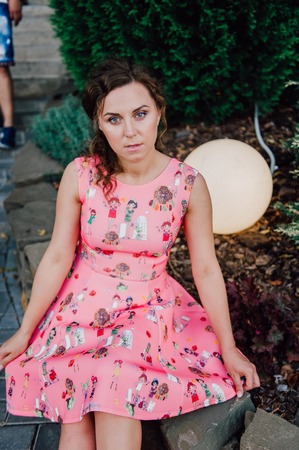 Beautiful brunette girl posing in pink dress outside near tropical plantsの写真素材