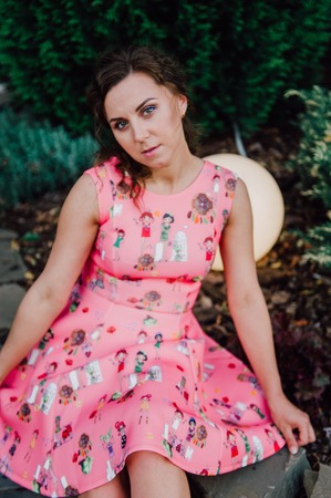 Beautiful brunette girl posing in pink dress outside near tropical plantsの写真素材