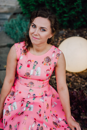 Beautiful brunette girl posing in pink dress outside near tropical plantsの写真素材