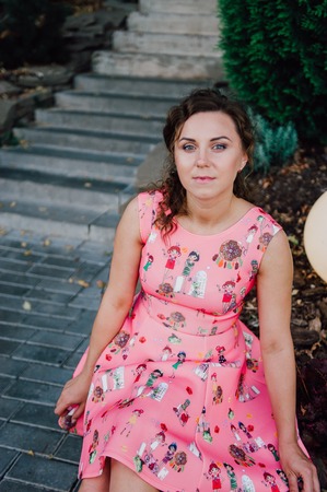 Beautiful brunette girl posing in pink dress outside near tropical plantsの写真素材
